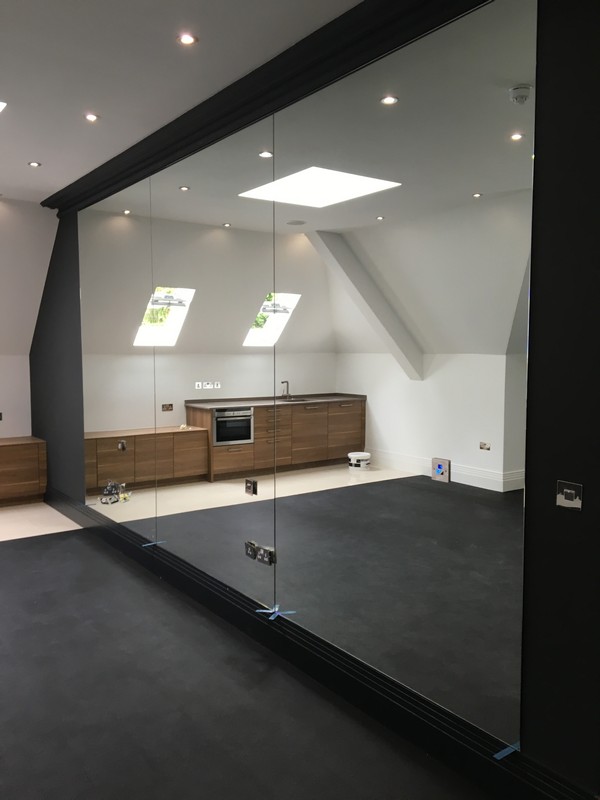 Frameless glass partition in loft conversion by Mile End glaziers